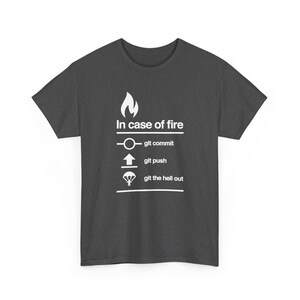 May include: A dark grey short-sleeve t-shirt featuring a white graphic with a flame icon and the text In case of fire, followed by three lines: a circle icon with git commit, an upward arrow with git push, and a parachute icon with git the hell out.