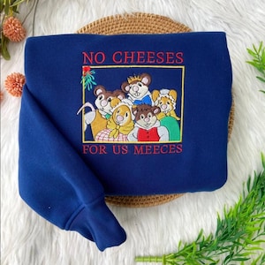 May include: A navy blue sweatshirt with the embroidered text "NO CHEESES FOR US MEECE" in red. The design features a group of cartoon mice in a yellow rectangular frame. The mice are wearing various outfits.