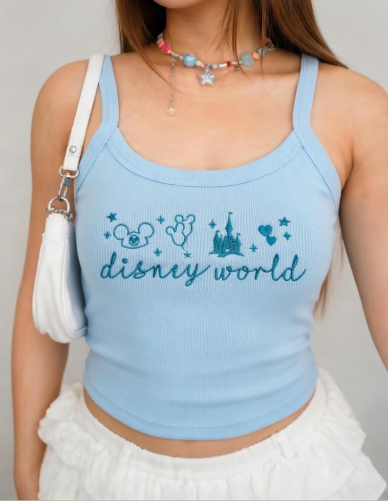 Peut inclure: D&eacute;bardeur c&ocirc;tel&eacute; bleu clair avec un motif Disney World brod&eacute; en bleu plus fonc&eacute;. Le motif comprend Mickey Mouse, des ballons, un ch&acirc;teau et des &eacute;toiles. Le d&eacute;bardeur a une encolure d&eacute;gag&eacute;e et de fines bretelles.