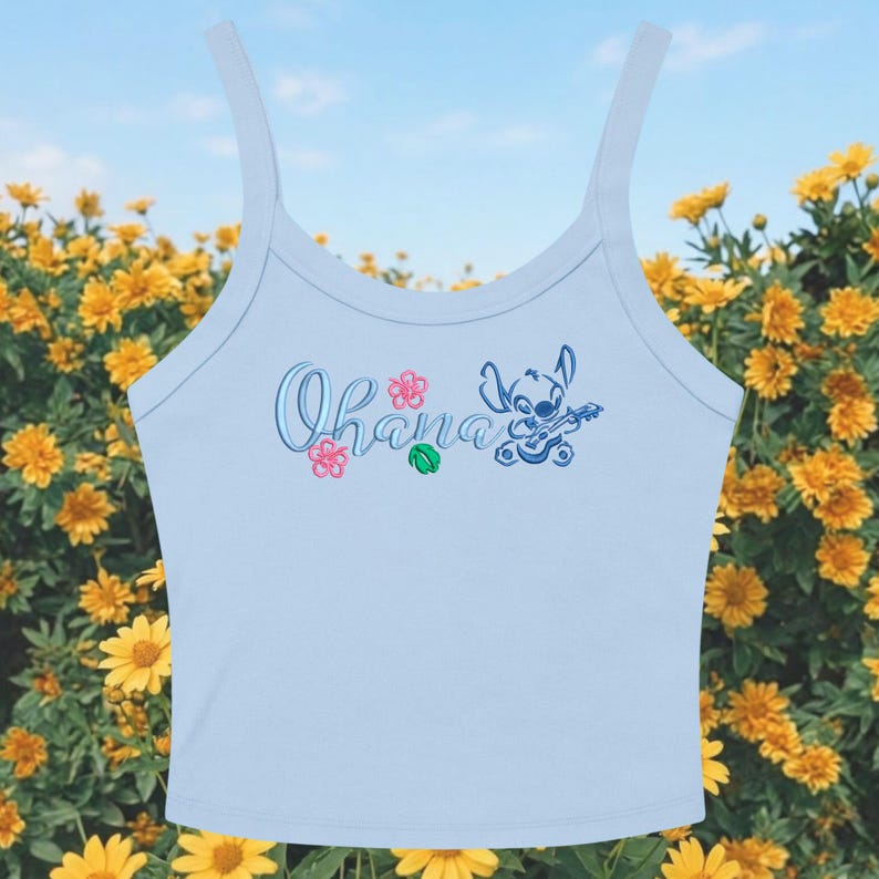 May include: Light blue tank top with the word "Ohana" in script, along with a cartoon character playing a ukulele. Pink and green floral accents are also present. The top has thin straps and a scoop neckline.