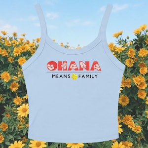 May include: Light blue tank top with the word "OHANA" in red, with a floral design, above the words "MEANS FAMILY" in black. A yellow flower graphic is between the words "MEANS" and "FAMILY". The tank top has thin straps.