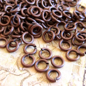 May include: A large pile of small, copper-colored jump rings. The rings are about 5mm in diameter and are perfect for jewelry making.