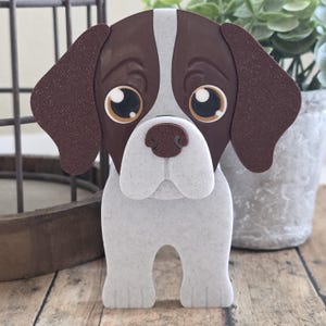 Op de afbeelding: Een bruin en wit cartoonhondje met grote bruine ogen. De hond staat op alle vier poten en heeft een bruine neus.