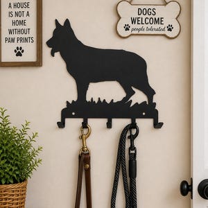 Könnte beinhalten: Schwarzer Metall-Hunde-Leinenhalter mit einer Deutschen Schäferhund-Silhouette, mit vier Haken. Enthält ein Schild mit der Aufschrift "Dogs Welcome, people tolerated". Ein gerahmtes Schild sagt "A house is not a home without paw prints."