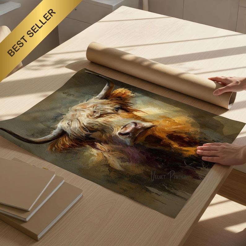 May include: A print of a Highland cow with long, shaggy fur in shades of brown, orange, and white. The artwork is on a table with a rolled-up poster and notebooks. A gold banner in the upper left corner reads "BEST SELLER".