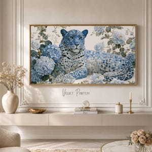 Könnte beinhalten: Ein gerahmter Wandkunstdruck mit einem blauen Leoparden inmitten blauer floraler Elemente. Das Fell des Leoparden ist mit blauen floralen Mustern versehen, und er ist von blauen Hortensien und Rosen umgeben. Der Druck hat einen goldenen Rahmen und den Text "Velvet Printery".