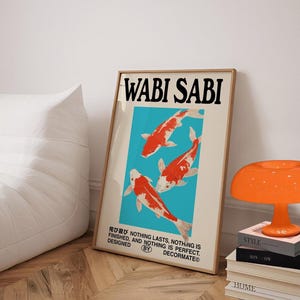 May include: A framed art print with the words "WABI SABI" in bold black letters. The artwork features three orange and white koi fish against a teal background. The print also includes Japanese text and the phrase "NOTHING LASTS, NOTHING IS FINISHED, AND NOTHING IS PERFECT."
