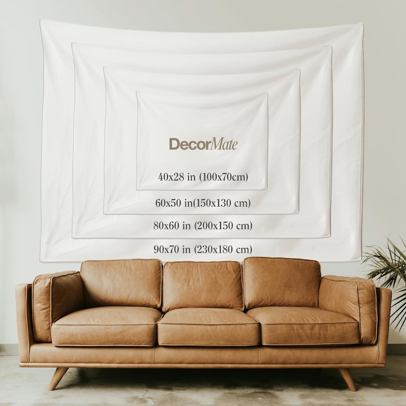 Puede incluir: Un tapiz de pared blanco con el texto "DecorMate" y opciones de tama&ntilde;o: 100x70cm, 150x130 cm, 200x150 cm y 230x180 cm. Un sof&aacute; de cuero marr&oacute;n se encuentra debajo del tapiz. El tapiz se muestra en una pared blanca.