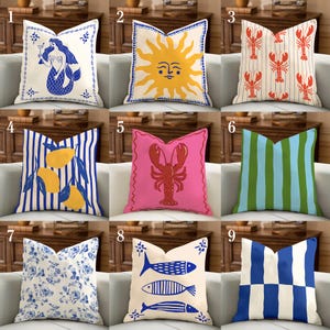 May include: A selection of decorative cushions with diverse patterns. Designs include a mermaid, sun, lobsters, lemons, fish, and stripes. The colour palette features blue, yellow, pink, green, and white. The square cushions are arranged on a white sofa.