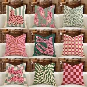 May include: A collection of nine square throw cushions featuring various patterns including pink leopards, tigers, cheetahs, green leaves, and checkered designs in shades of pink, red, green, and cream, arranged in a three-by-three grid layout.