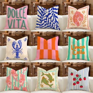 May include: Nine decorative throw pillows with various designs. Pillows include text, stripes, and graphic illustrations of a lobster, tigers, fish, and tomatoes. Colors include pink, blue, orange, green, and white.