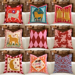Pode incluir: Nove almofadas decorativas com vários designs. As almofadas apresentam estampas de animais, padrões geométricos e motivos celestes. As cores incluem vermelho, rosa, laranja, azul e dourado. As almofadas são quadradas e parecem ser de tecido.
