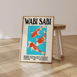 May include: Framed art print featuring the words "WABI SABI" in bold black letters. The artwork depicts three koi fish with red and white markings against a light blue background. The print includes Japanese text and the phrase "NOTHING LASTS, NOTHING IS FINISHED, AND NOTHING IS PERFECT."