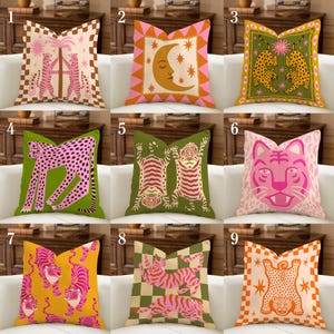 May include: A collection of nine square throw pillows featuring various graphic prints including tigers, leopards, moons, and stars in vibrant color palettes of pink, orange, green, and yellow with checkered and patterned borders.