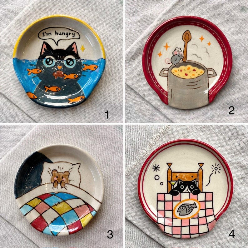 K&ouml;nnte beinhalten: Set aus vier Keramik-L&ouml;ffelablagen mit skurrilen Katzen- und Maus-Designs. Jede Ablage zeigt eine einzigartige Illustration: eine Katze mit Fischen, eine kochende Maus, eine Maus im Bett und eine Katze an einem Tisch mit einem Fisch. Die Ablagen haben farbenfrohe R&auml;nder und verspielte Bilder.