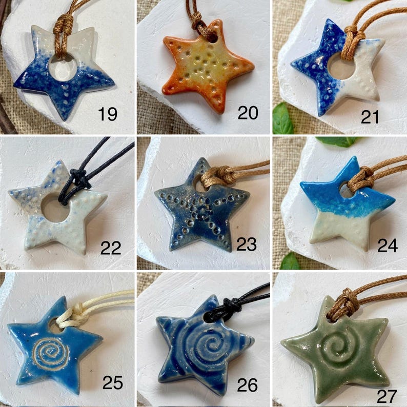 May include: A selection of ceramic star-shaped pendants in shades of blue, orange, and green. Each pendant is strung on a cord. Some stars have a central hole, while others feature textured or spiral patterns. The pendants are numbered 19 to 27.