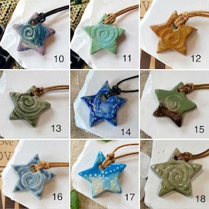 May include: A selection of handmade ceramic star pendants in various colours, including blue, green, and brown. Each star features a unique spiral design and is strung on a leather cord. The pendants are displayed on a white surface.