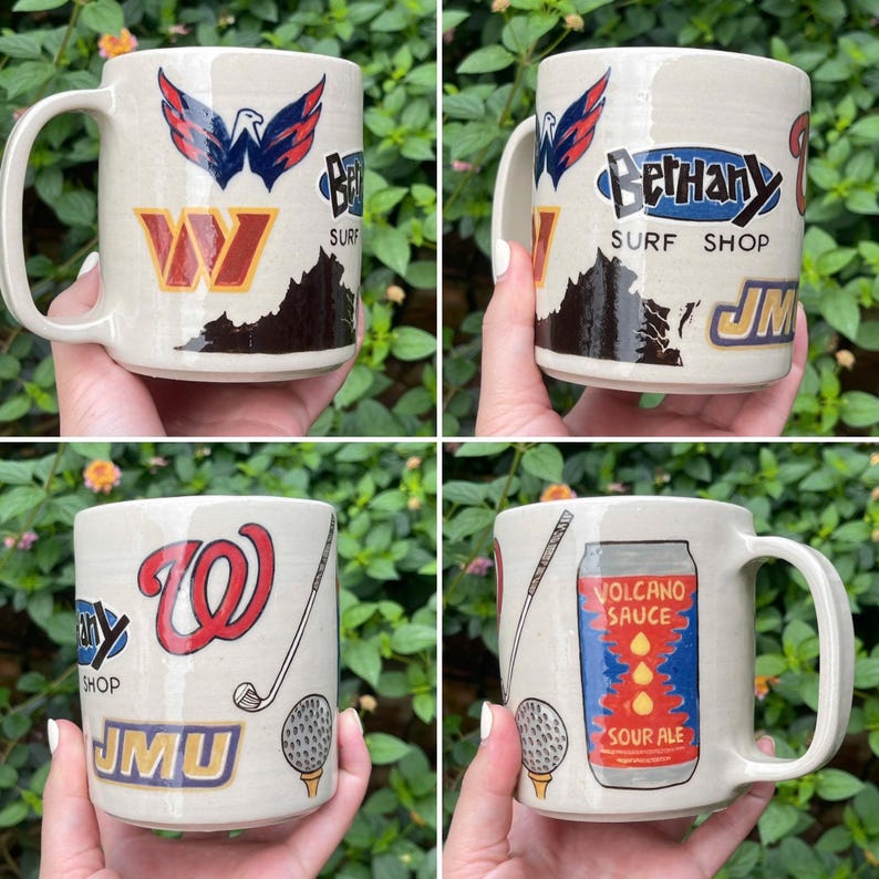 May include: Cream-colored ceramic mugs with various designs. One mug features a red and blue eagle emblem and the letter "W". Another mug has "Bethany Surf Shop" text and a mountain graphic. The third mug displays a golf theme, and the last mug has a "Volcano Sauce Sour Ale" label.