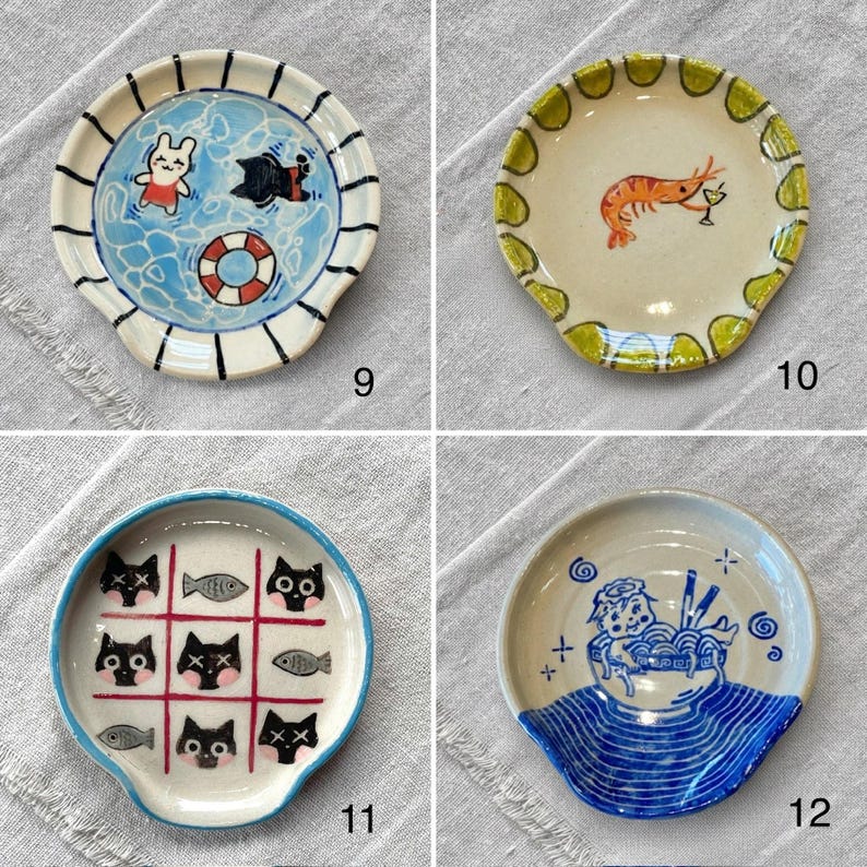 K&ouml;nnte beinhalten: Vier kleine Keramik-L&ouml;ffelablagen mit einzigartigen Designs. Eines zeigt eine Poolszene mit einem Kaninchen und einer Fledermaus, ein anderes eine Garnele mit einem Getr&auml;nk, ein drittes mit Katzentictactoe und das letzte mit einer Ramen-Sch&uuml;ssel.