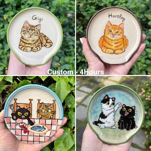 K&ouml;nnte beinhalten: Vier Keramik-L&ouml;ffelablagen mit Katzenillustrationen. Eine zeigt eine getigerte Katze namens Gigi, eine andere eine orangefarbene Katze namens Hartley. Die anderen beiden zeigen Katzenszenen mit einem Esstisch und spielenden Katzen. Der Text "Custom - 4Hours" ist ebenfalls sichtbar.