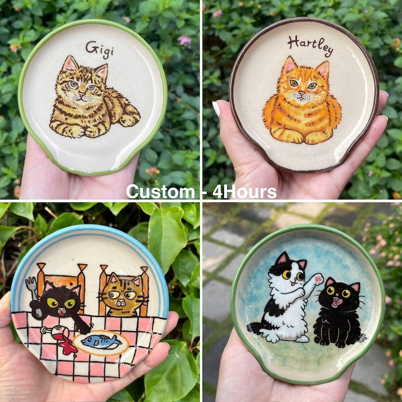K&ouml;nnte beinhalten: Vier Keramik-L&ouml;ffelablagen mit Katzenillustrationen. Eine zeigt eine getigerte Katze namens Gigi, eine andere eine orangefarbene Katze namens Hartley. Die anderen beiden zeigen Katzenszenen mit einem Esstisch und spielenden Katzen. Der Text "Custom - 4Hours" ist ebenfalls sichtbar.