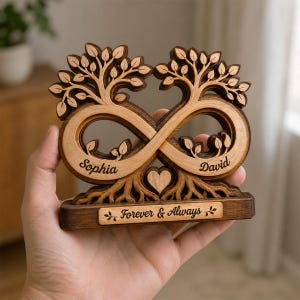 May include: A wooden decorative ornament featuring two intertwined trees forming an infinity symbol shape. The names Sophia and David are engraved on the base of the trees, with a small heart in the center. A rectangular plaque reads Forever & Always.