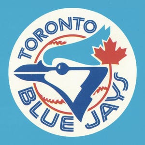May include: A circular sticker featuring the Toronto Blue Jays logo. The design includes a blue jay bird silhouette in shades of blue, a red maple leaf, and a baseball graphic. The text TORONTO BLUE JAYS is printed in blue along the circular border.