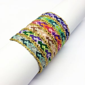 May include: A stack of colorful friendship bracelets with gold trim. The bracelets are woven with a chevron pattern and are arranged in a spiral.