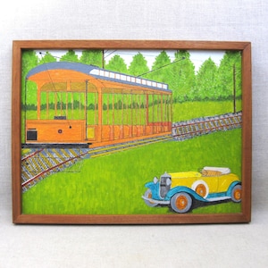 May include: A framed painting of a vintage orange trolley car on a track with a yellow and blue vintage car parked in front of it. The painting is set against a green grassy background with trees in the distance.