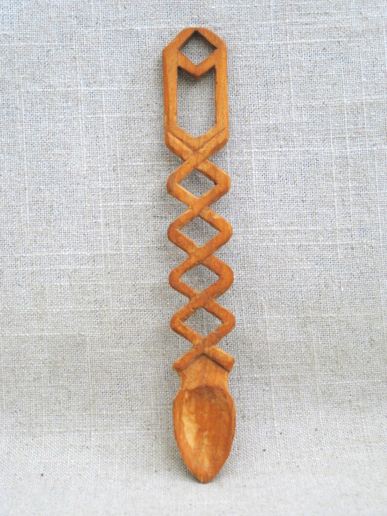 Peut inclure: Une cuill&egrave;re en bois avec un motif sculpt&eacute;. La cuill&egrave;re est brune et a un long manche avec un motif d&eacute;coratif. Le bol de la cuill&egrave;re est arrondi et lisse.