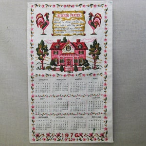 May include: A vintage kitchen towel with a 1976 calendar, a pink house, and two roosters. The towel features a prayer that reads "Lord, warm all the kitchen with Thy love and light it with Thy peace. Forgive me all my worry, and make my grumbling cease."