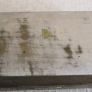 May include: A silver metal box with a worn, scratched surface. The box has a brown wooden trim around the edges.