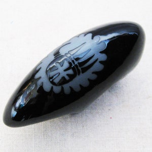 May include: A black ceramic egg-shaped vase with a white design of a stylized flower.