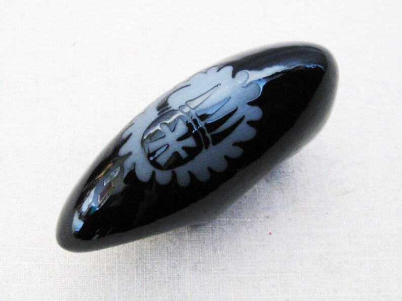 May include: A black ceramic egg-shaped vase with a white design of a stylized flower.