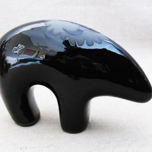 May include: A black ceramic bear figurine with a white design on its back. The bear is standing on all fours and has a glossy finish.