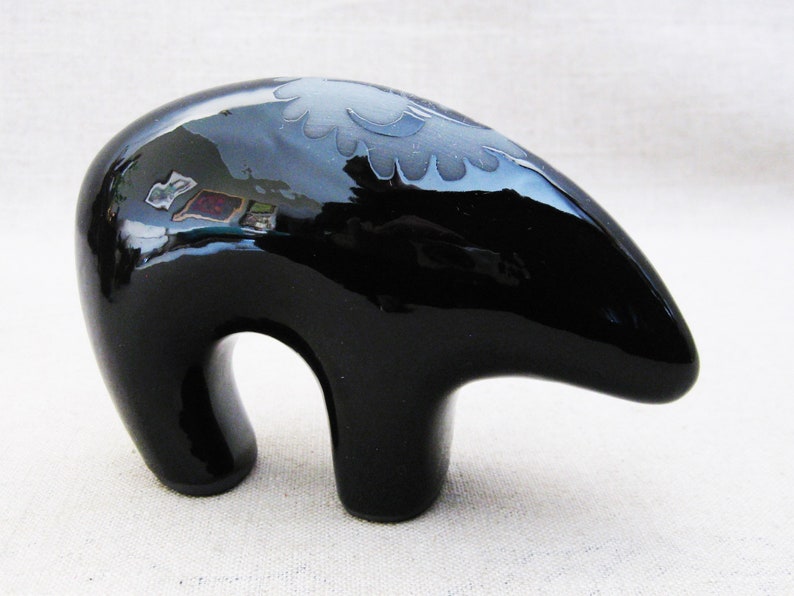 May include: A black ceramic bear figurine with a white design on its back. The bear is standing on all fours and has a glossy finish.