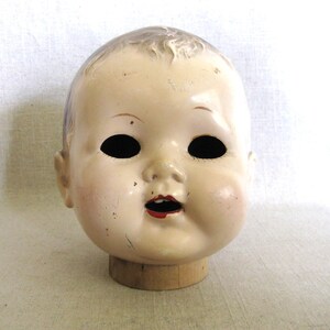 Vintage Composite Doll Head, Large Creepy Male with NO Eyes, perfect for all kinds of uses, from adding to a collection, to Halloween décor, or as Doll Parts and Supplies for Doll Repair to Assemblage Sculpture. Listing is for 1 doll head, other props are NOT included. Mid-Century Toys. He has a wooden Neck, it is attached from inside, but is loose, not connected to head at neck.