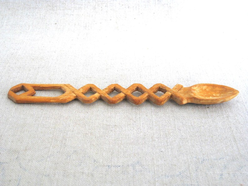 Peut inclure: Une cuill&egrave;re en bois avec un design sculpt&eacute; et complexe. La cuill&egrave;re est en bois brun clair et a un bol arrondi. Le manche est d&eacute;cor&eacute; d'une s&eacute;rie de formes de diamants.