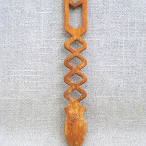 Peut inclure: Une cuill&egrave;re en bois avec un motif g&eacute;om&eacute;trique sculpt&eacute;. La cuill&egrave;re est brune et a une pointe pointue.