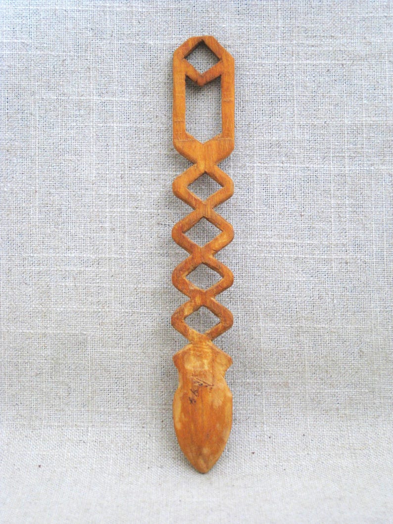Peut inclure: Une cuill&egrave;re en bois avec un motif g&eacute;om&eacute;trique sculpt&eacute;. La cuill&egrave;re est brune et a une pointe pointue.