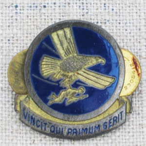 May include: A gold and blue enamel pin with an eagle and a running figure. The pin has the text "Vincit Qui Primum Serit" and the number "230842".