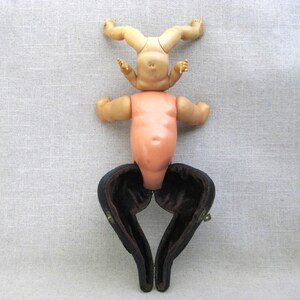 May include: A vintage doll with a nude torso and limbs, with a black velvet case for the legs. The doll's head and arms are missing.