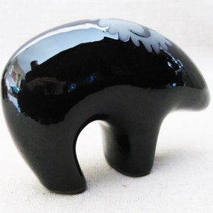 May include: A black ceramic bear figurine with a white design on its back. The bear is standing on all fours and has a glossy finish.