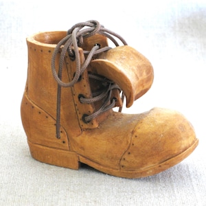 May include: A wooden boot with brown laces, carved in detail. The boot is a decorative piece and has a rustic, vintage look.