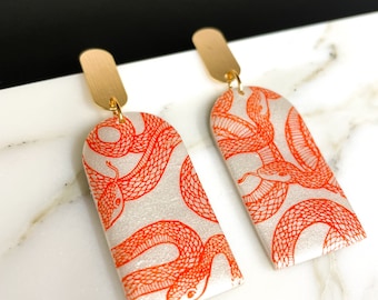 Pearlescent White Arch Tombstone with Orange Snake Silkscreen Dangling from  Gold Plated Oval Studs | Polymer Clay Halloween Earrings
