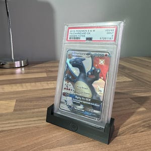 May include: A graded Pokemon trading card featuring Charizard GX from the Hidden Fates expansion. The card is in a protective case with a 9/10 mint condition rating.