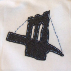 Peut inclure: Une appliqu&eacute; en feutre marron du pont de Brooklyn avec des coutures bleues sur un fond blanc.
