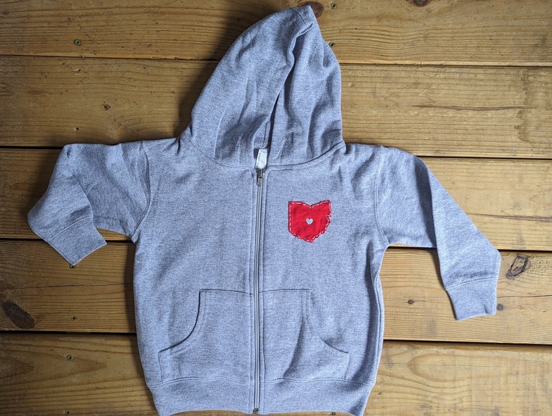 May include: A grey zip-up hoodie with a red felt Ohio state outline with a small heart in the centre.