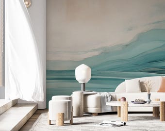 May include: A white couch with pillows and a throw blanket sits in a living room with a light blue and white abstract wall mural. A white lamp with a round shade sits on a white coffee table with a white stool and a wooden stool.