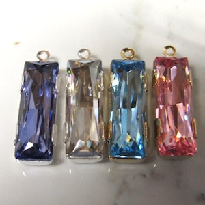 May include: Four rectangular glass pendants with gold-toned metal loops. The pendants are in shades of blue, pink, clear, and purple.